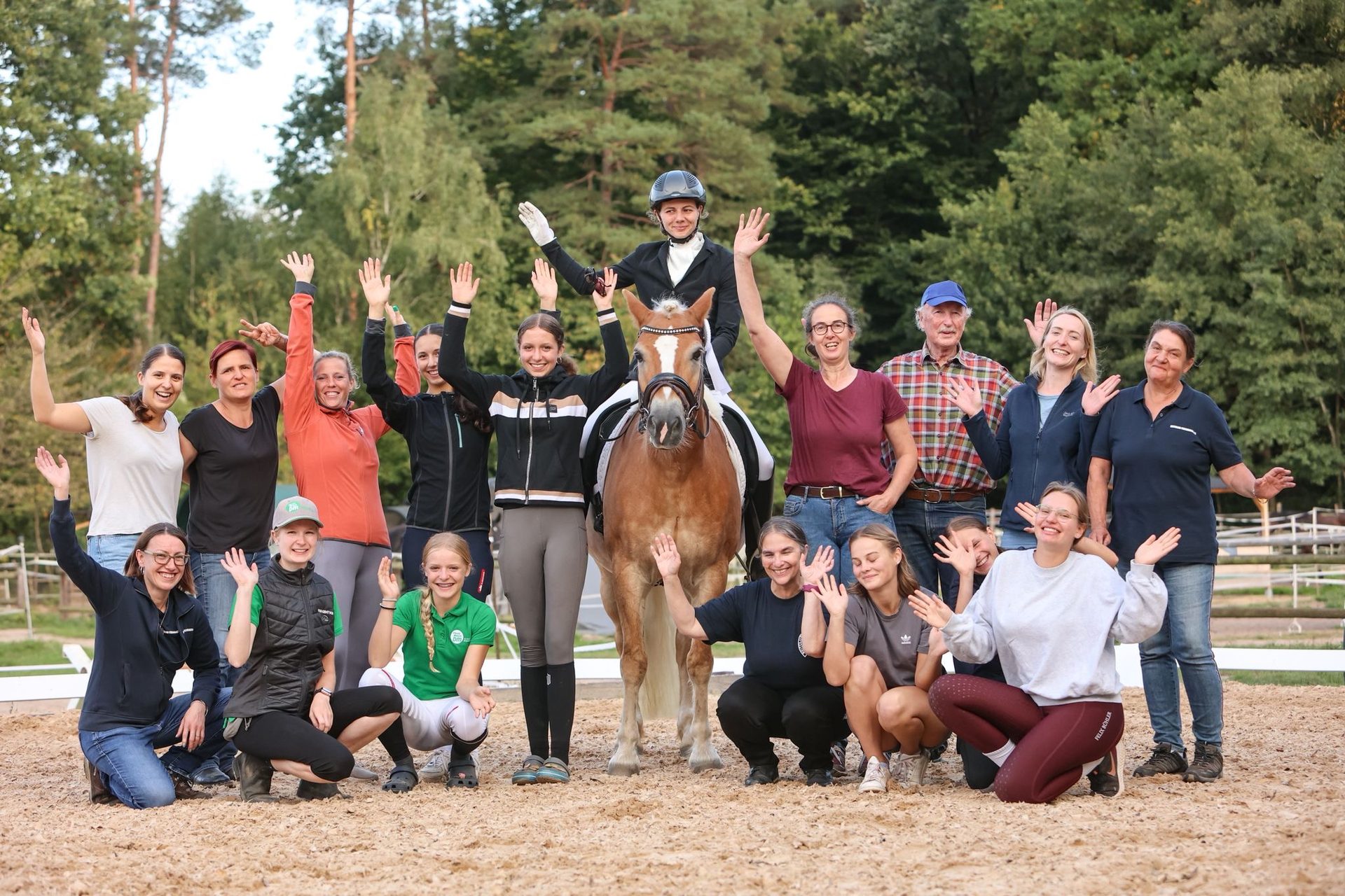 Winkende Mitglieder des Reitclub Fischbach mit einem Haflinger vor der Waldkulisse